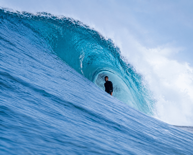 Surfer riding a blue barrel wave.