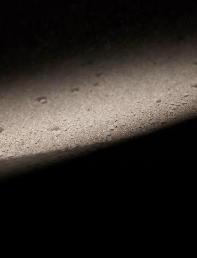 Close-up of a foamy surface, brightly lit from the top left against a dark background.