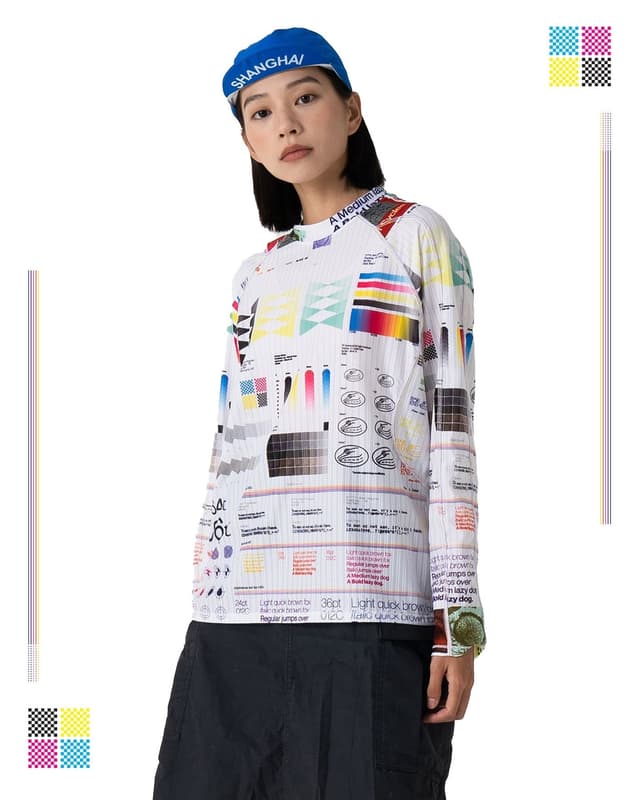 A person wearing a blue "SHANGHAI" beanie and a white long-sleeve shirt patterned with printer test page graphics.