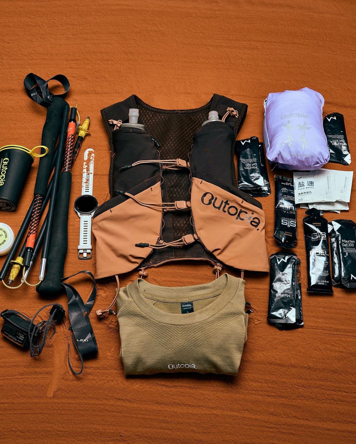 Flat lay of trail running gear, including a vest, trekking poles, smartwatch, energy gels, and a folded shirt, on an orange surface.