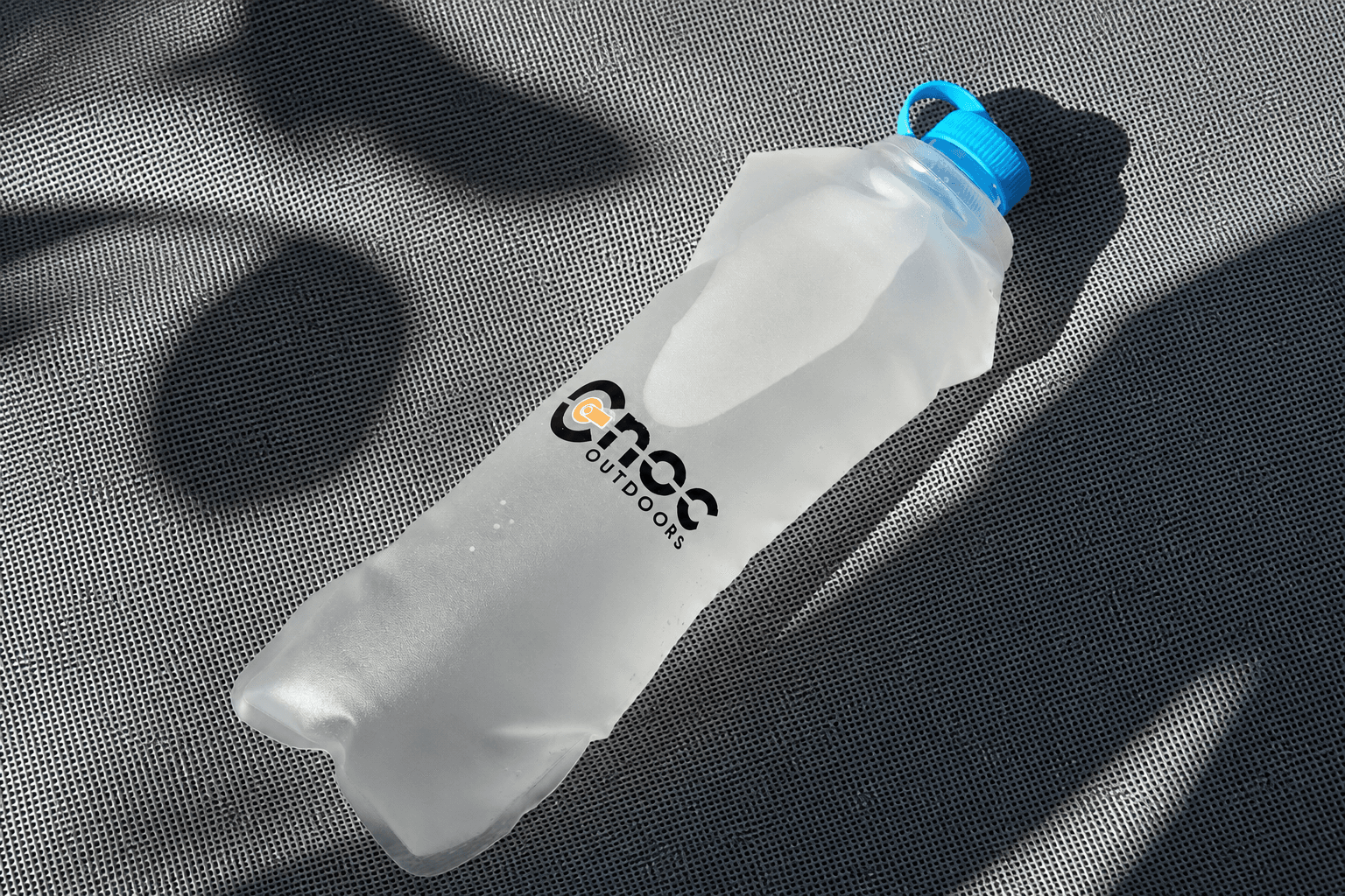 Translucent Cnoc Outdoors collapsible water bottle with a blue cap.