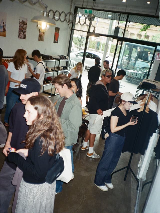 Customers browsing clothing and hats in a busy, casual store.