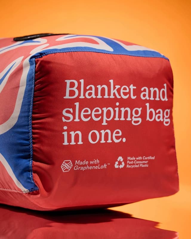 Red and blue packaged blanket or sleeping bag, partly featuring a Union Jack pattern, with text reading: "Blanket and sleeping bag in one," "Made with GrapheneLoft™," and "Made with Certified Post-Consumer Recycled Plastic."