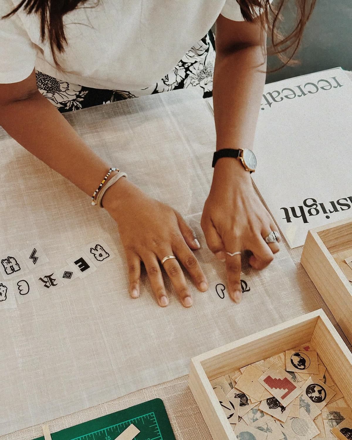 Hands placing black letter stickers on light fabric.