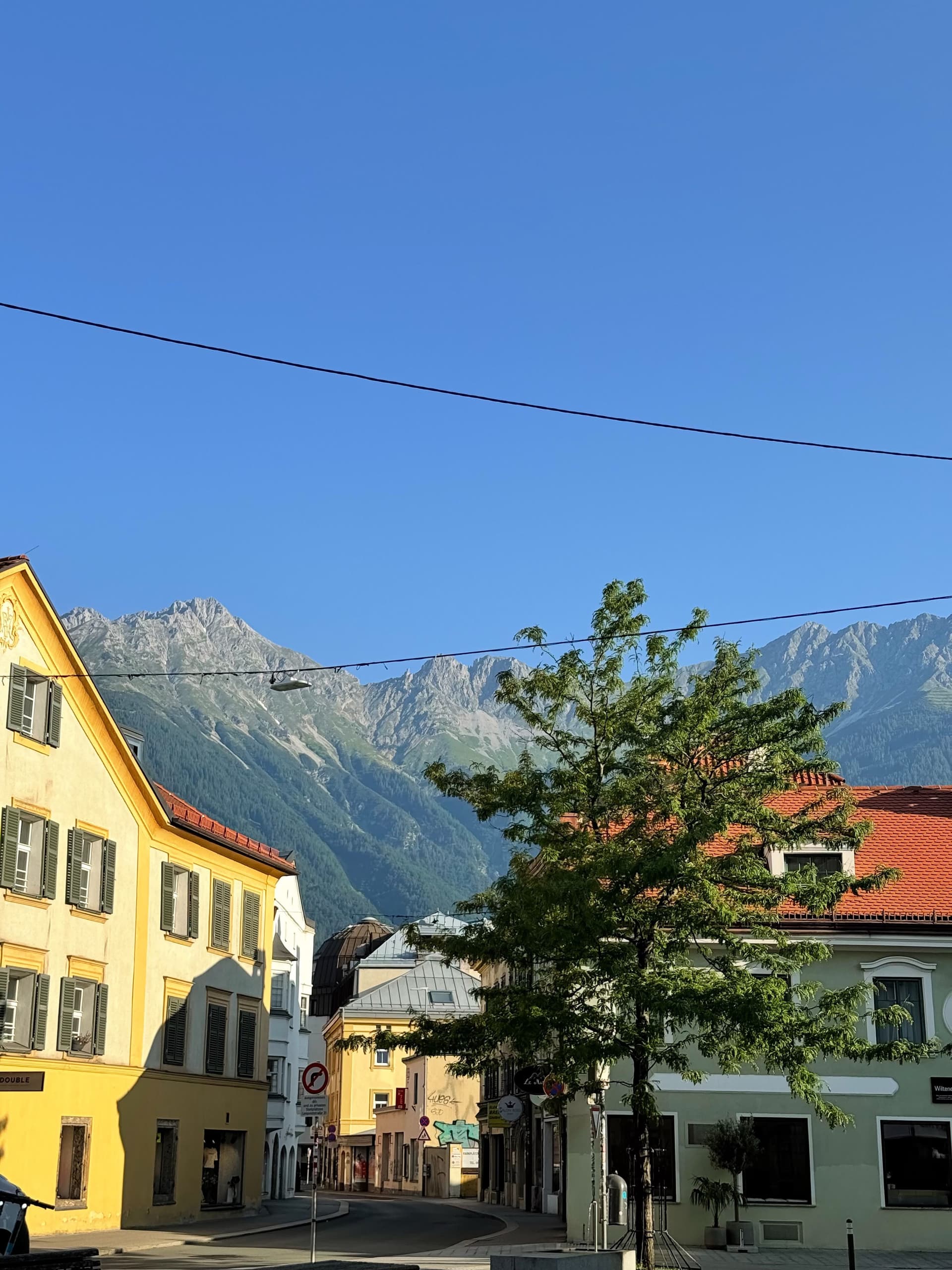 A town street with colorful buildings and distant mountains under a clear blue sky.