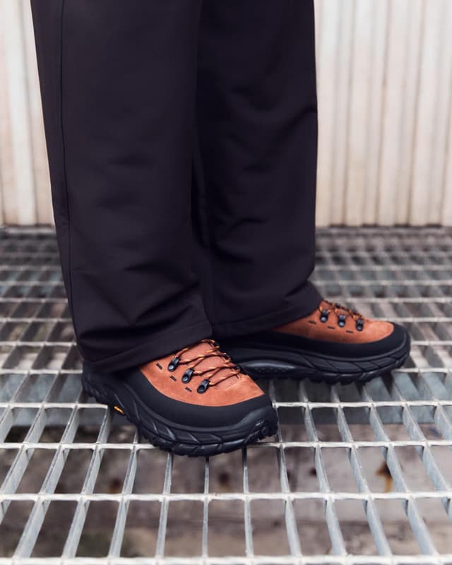 Legs in black pants and brown and black hiking shoes standing on a metal grate.