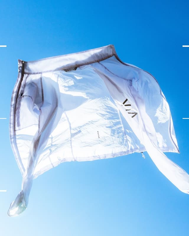 A translucent white jacket billows against a bright blue sky.