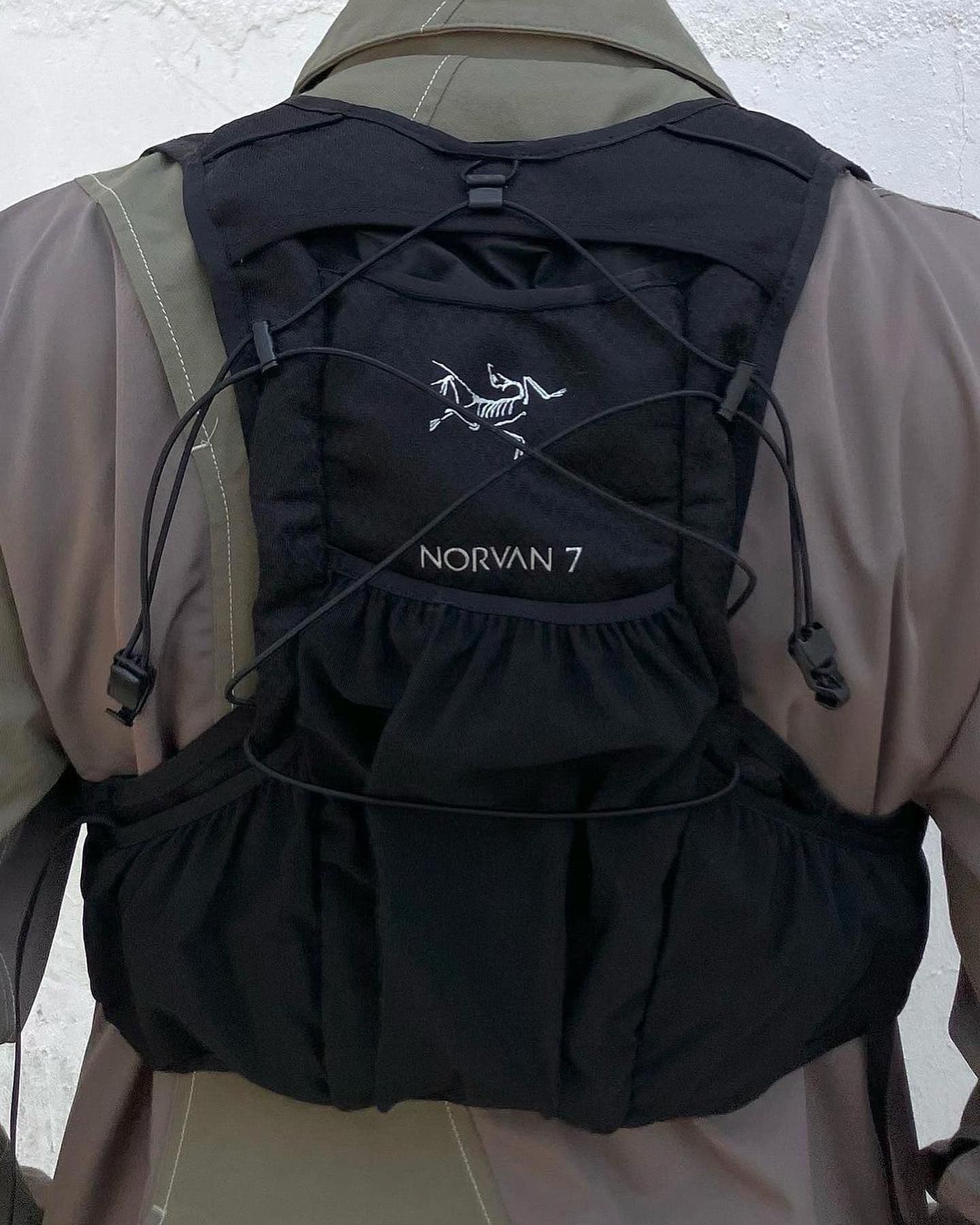 Black Arc'teryx Norvan 7 running vest worn over a two-tone jacket.