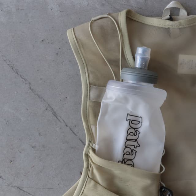 A tan running vest with a white Patagonia soft flask in its pocket.