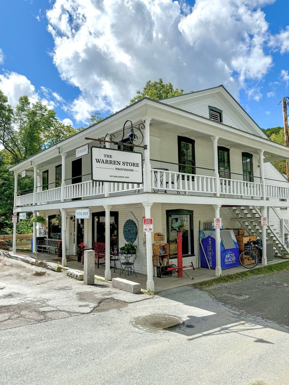 A white two-story building with a wrap-around porch and a sign reading "The Warren Store Provisions."