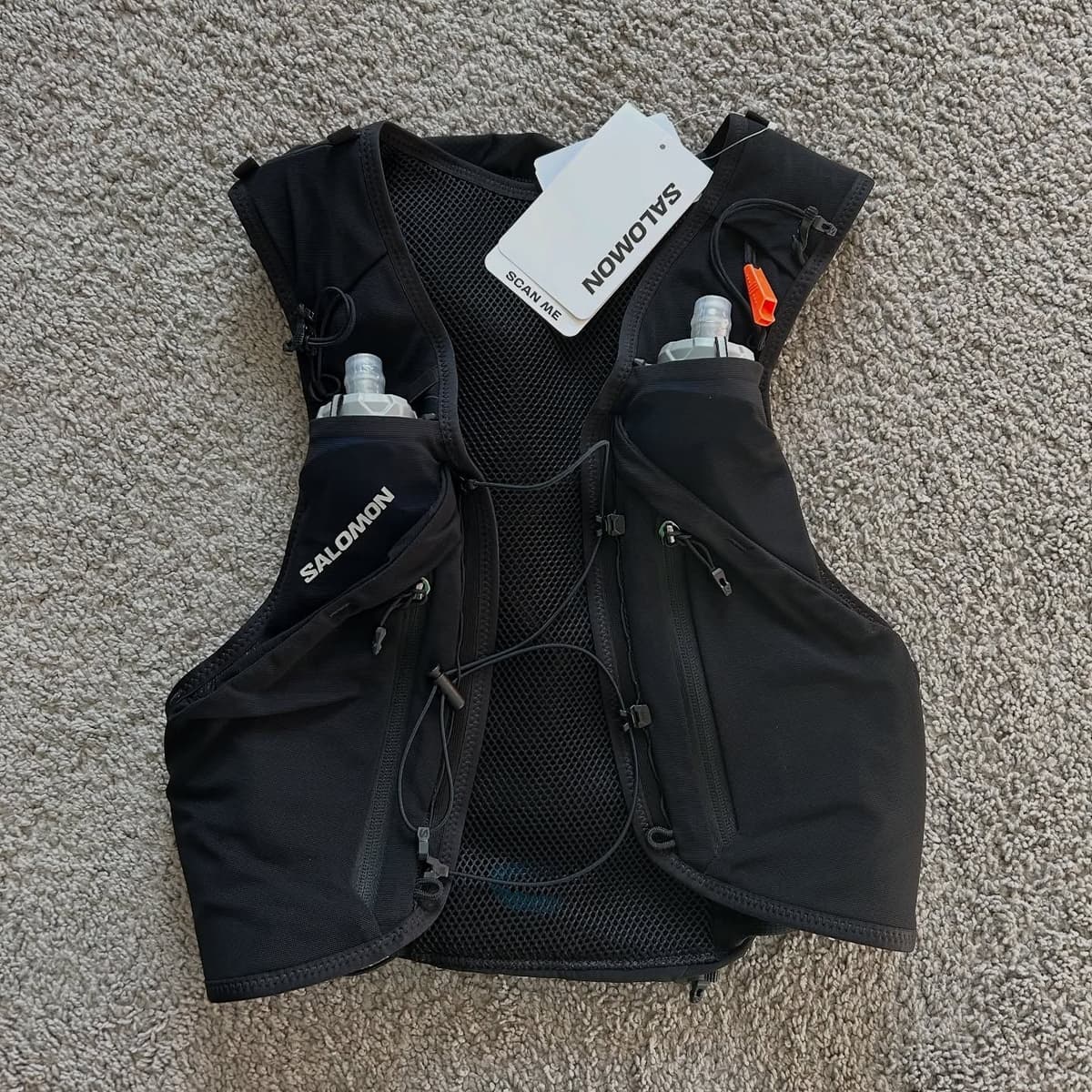Black Salomon running hydration vest with two soft bottles and an orange whistle.