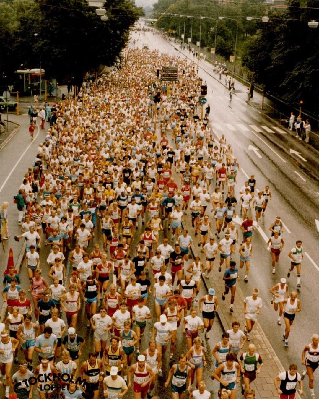 Hundreds of runners stream down a wet city street during the Stockholm Loppet 1985.