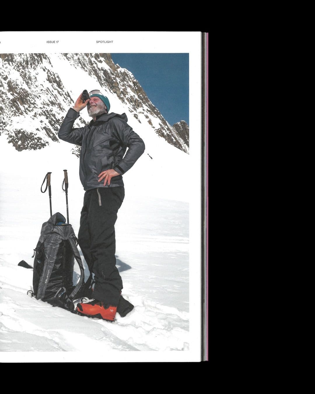 A man in ski gear drinks from a bottle in a snowy mountain landscape.