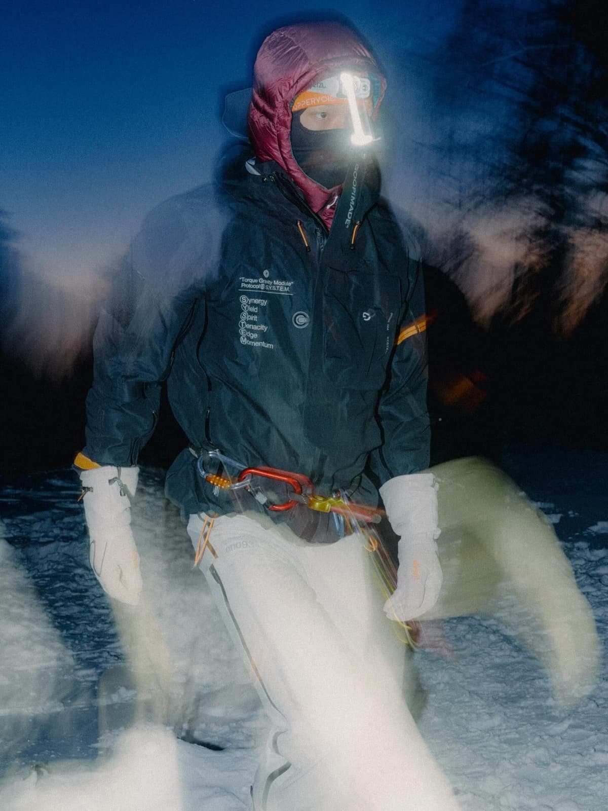 A pink, yellow, and black trail running vest packed with shoes and a red helmet, with trekking poles strapped to the bottom.