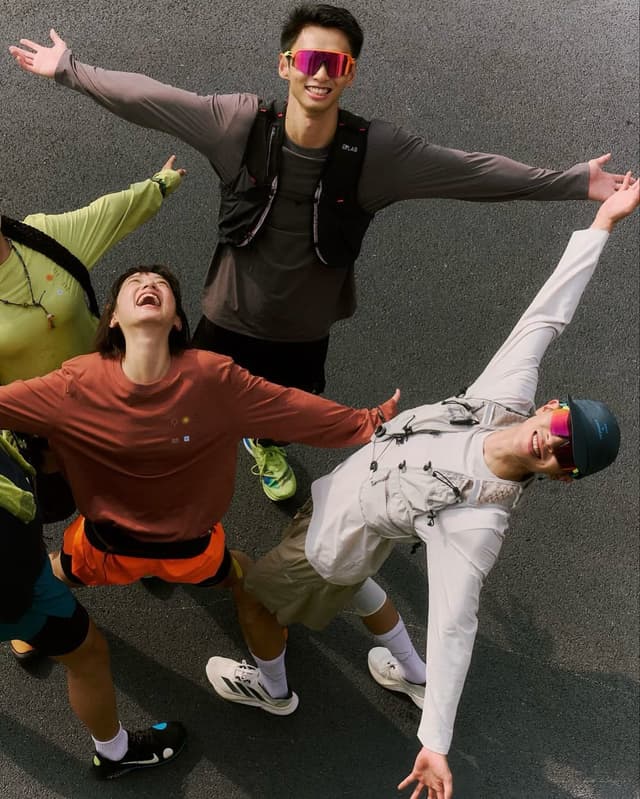 Four people in athletic wear looking up and smiling with arms outstretched.