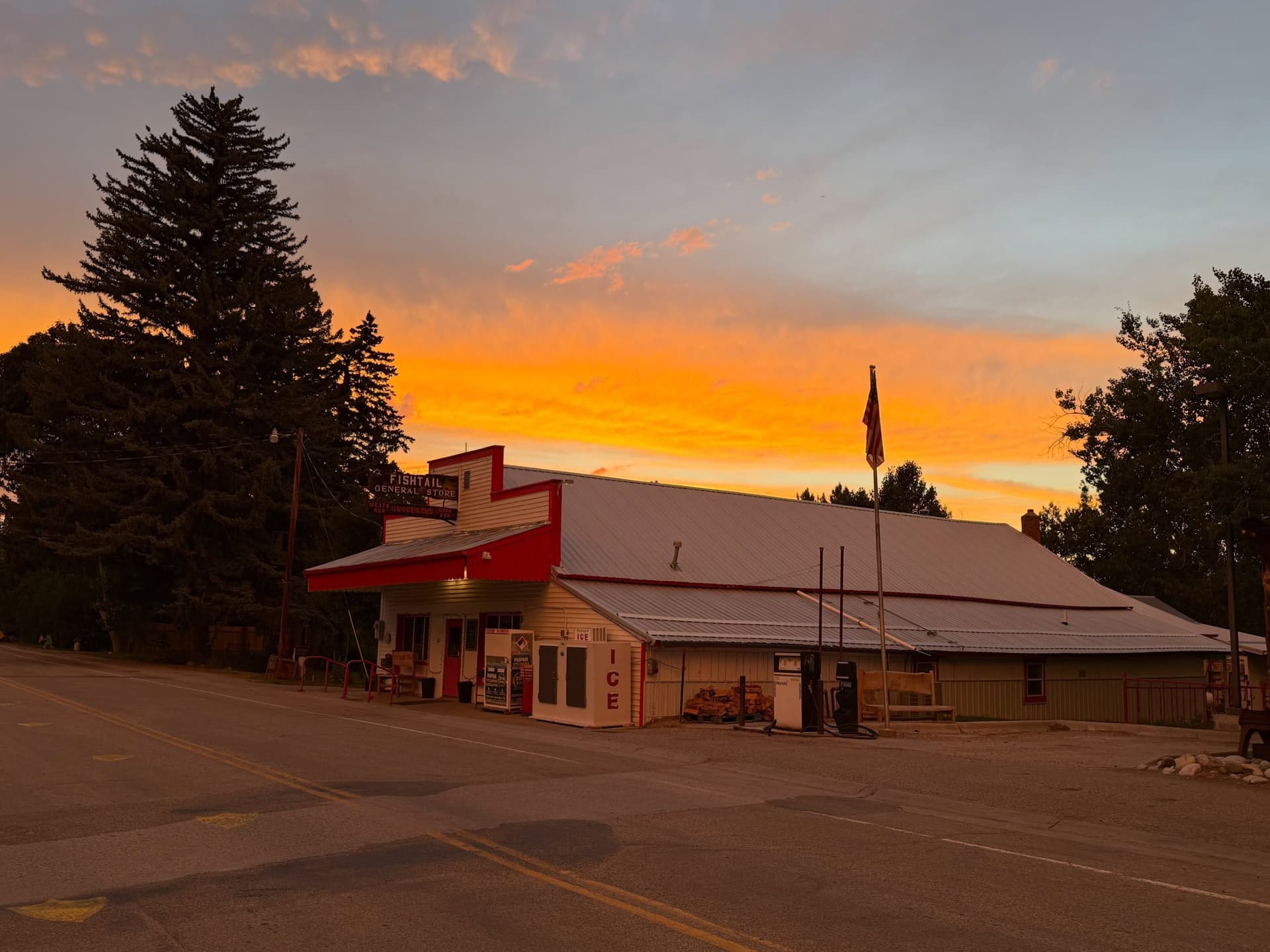 A general store and gas station under a vibrant orange and yellow sunset sky.
