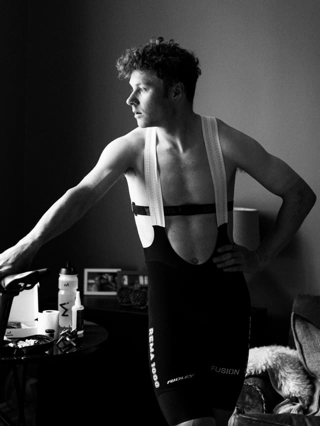 Black and white photo of a man in cycling bib shorts and a heart rate monitor, looking left.