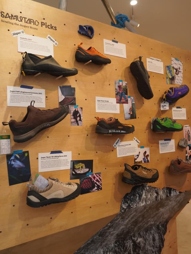 A wooden wall display titled "SAMUTARO Picks" showcasing various hiking and climbing shoes with descriptive cards and photos.