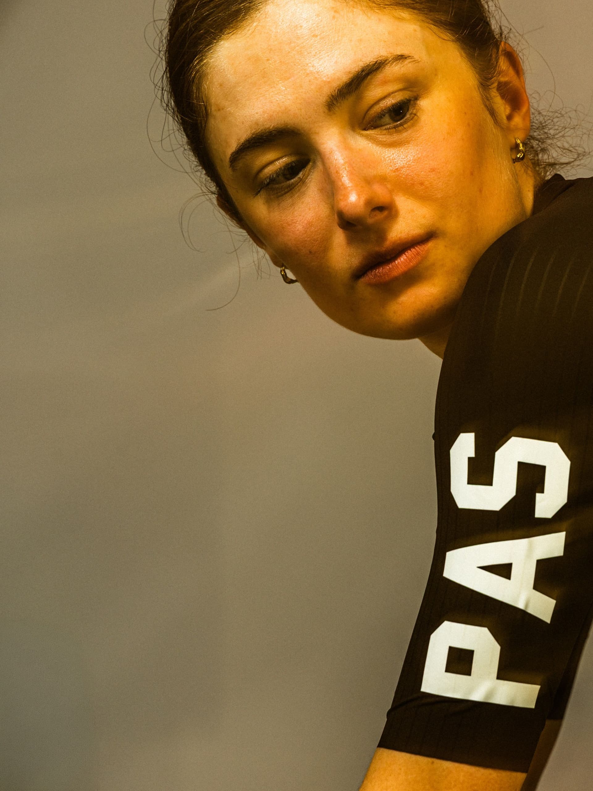 A woman in a dark athletic top with "PAS" visible on the side looks down.