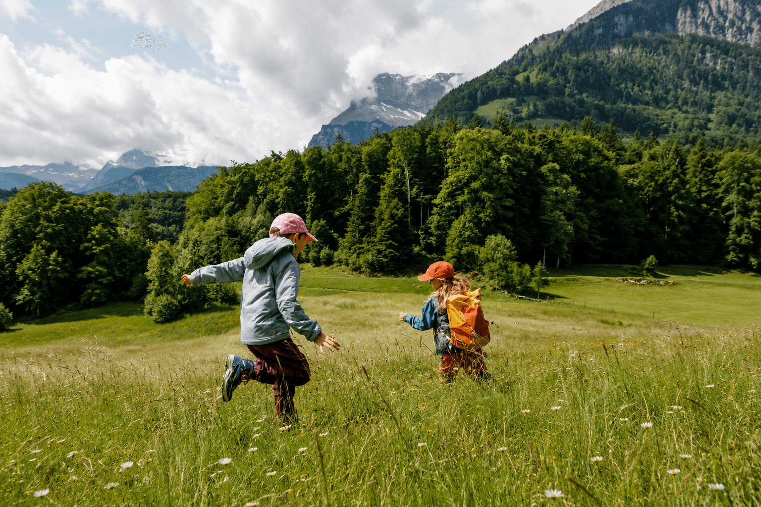 Two children playing in a sunlit mountain meadow.