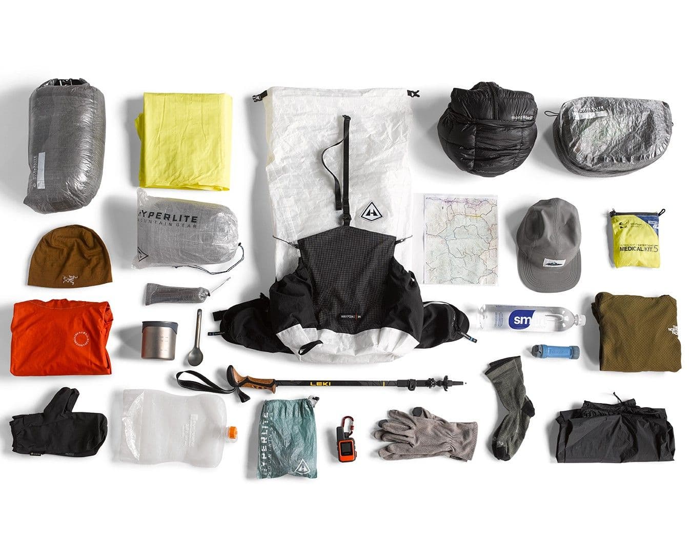 Overhead flat lay of ultralight backpacking gear on a white background.