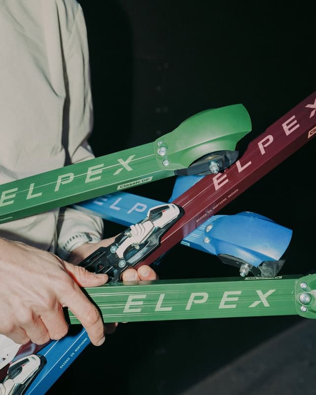 A person's hands hold multiple green, red, and blue ELPEX roller skis.
